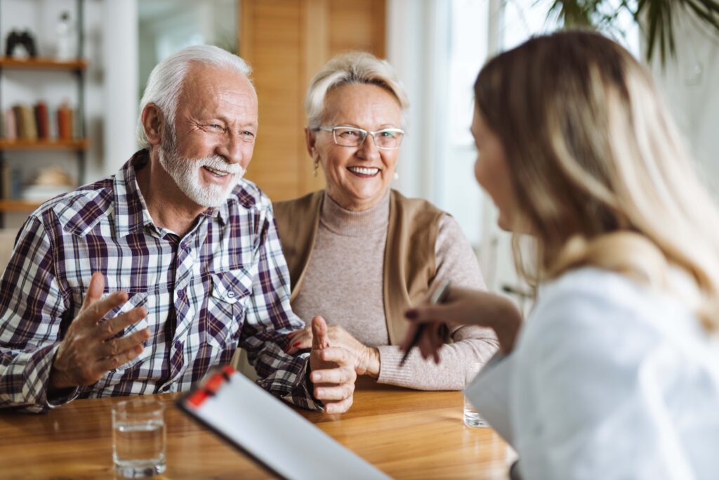 Smiling senior couple reviewing Medicare enrollment options with an insurance advisor at a table
