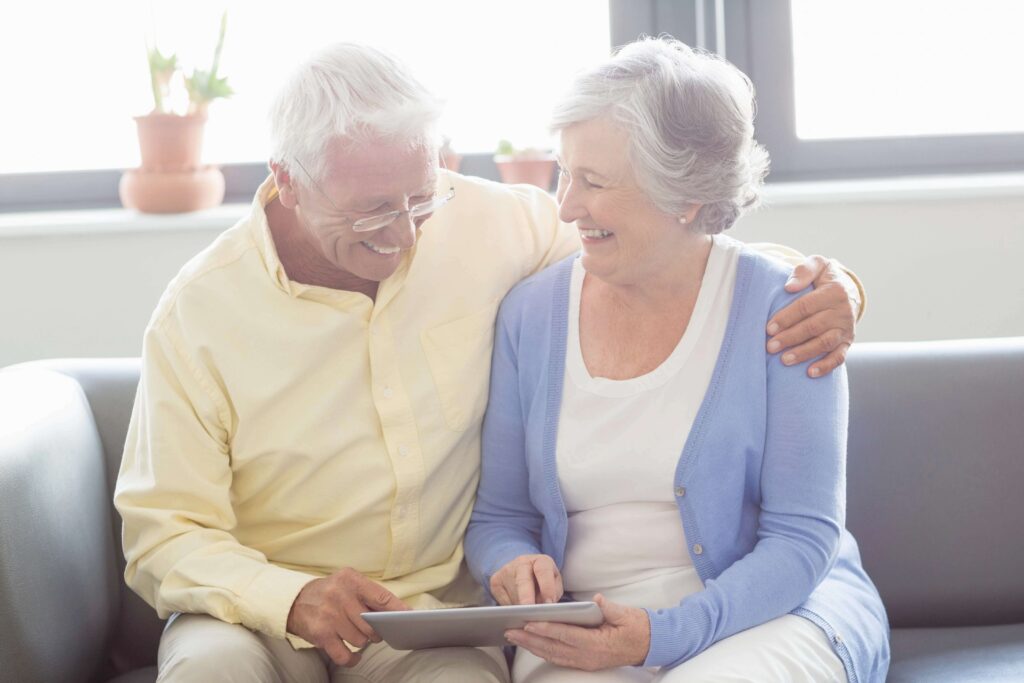 Senior couple smiling together while reviewing information on a tablet